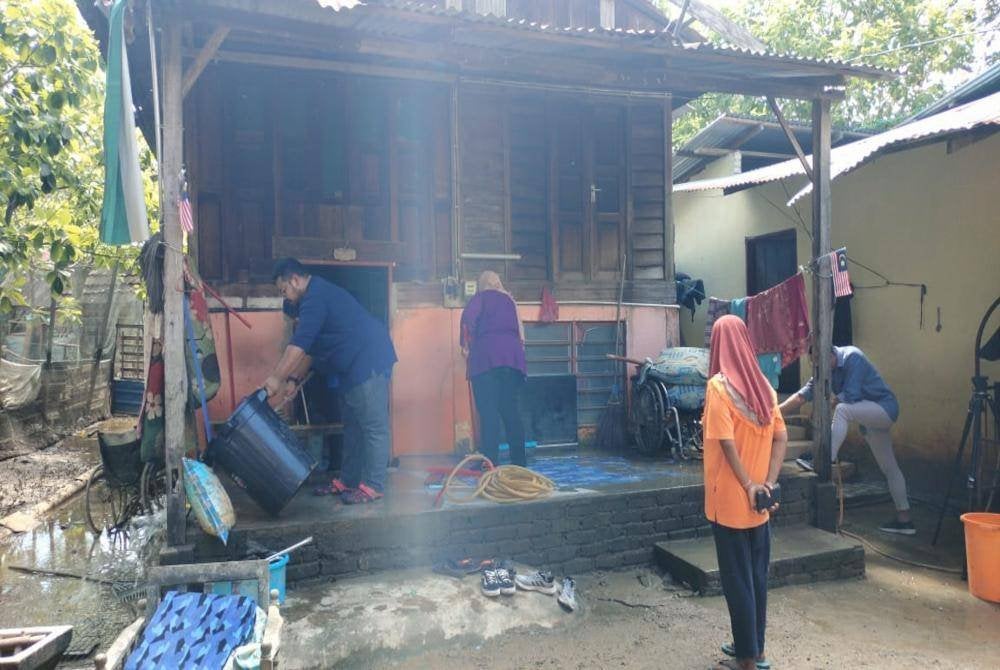 Sukarelawan Persatuan Atlet-Atlet Legenda Negeri Kedah membantu membersihkan rumah Hasnah daripada kesan banjir di Kampung Seberang Pumpong, Bakar Bata, Alor Setar pada Rabu.