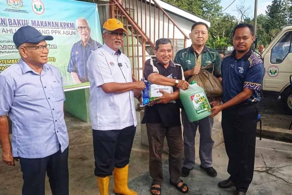 Mahfuz (dua dari kiri) menyampaikan sumbangan kepada pesawah yang terjejas akibat banjir dalam PPK Asun di Kampung Paya Tok Teh pada Khamis.
