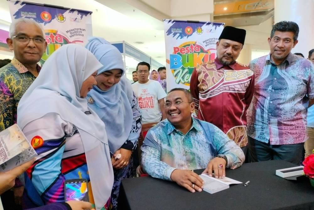 Muhammad Sanusi beramah mesra dengan peminat ketika menurunkan tanda tangan sebagai penulis buku bertajuk 'Dinding Sekeping Adik Seorang'.