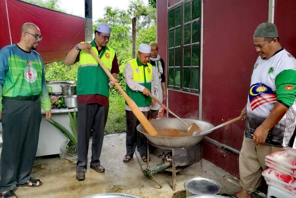 Ahmad (tiga dari kiri) meninjau Dapur Rakyat yang menyediakan makanan dimasak petugas sebelum diagihkan kepada mangsa banjir yang memerlukan.