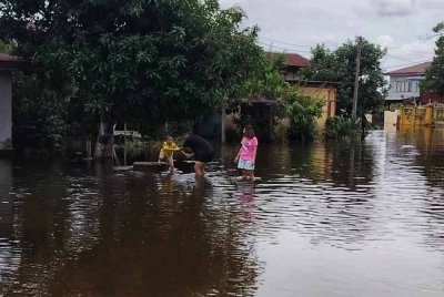 Sebuah keluarga di Pendang bermain air banjir yang memenuhi kawasan rumah mereka.