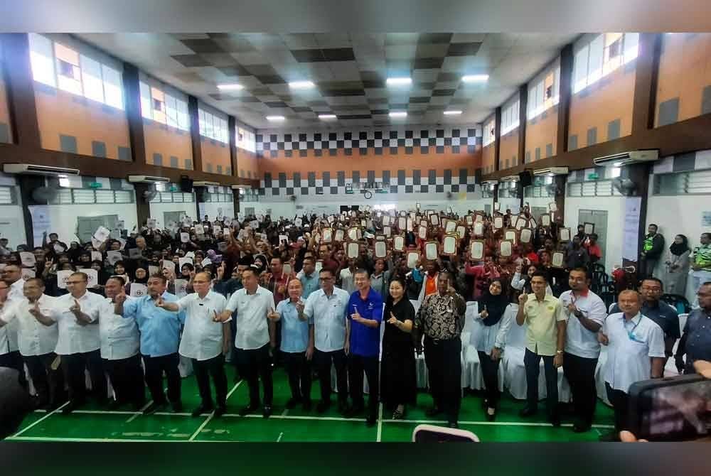 Wan Rosdy (lima dari kiri) bergambar kenangan bersama penerima surat hak milik tanah di Dewan Dato' Zaharuddin Abu Kassim, Temerloh pada Jumaat.