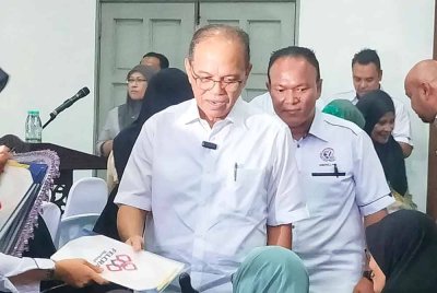 Wan Rosdy (tengah) ketika menyerahkan surat hak milik tanah kepada penerima di Dewan Dayo' Zaharuddin Abu Kasim, Temerloh pada Jumaat.