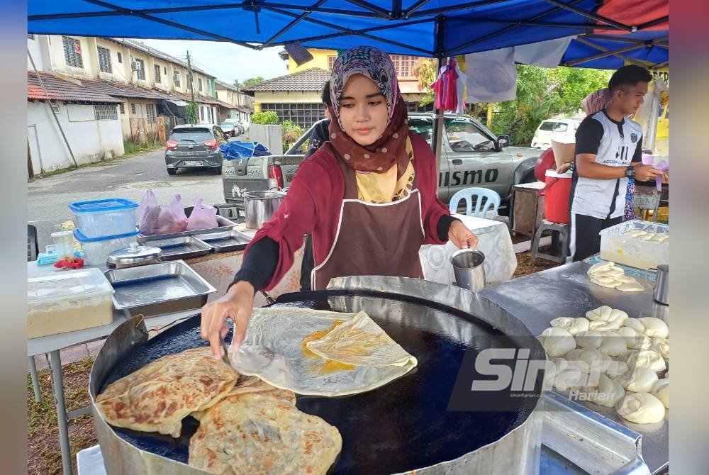 Nor Syazwani memasak roti canai telur tempahan pelanggan digerai ‘Roti Canai Abah’ di Indera Mahkota Dua di sini, pada Jumaat.