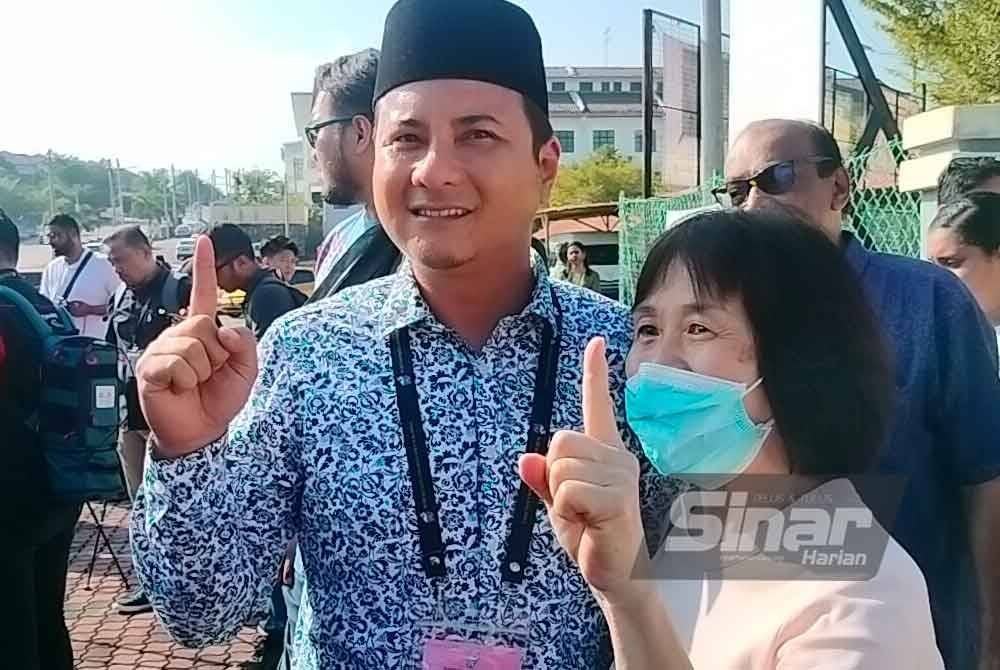 Syed Hussien ( kanan) bergambar dengan pengundi selepas selesai membuang undi di SMK Seri Perdana.