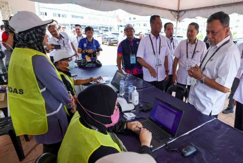 Ramlan (kanan) beramah mesra bersama petugas SPR ketika meninjau proses undi bagi PRK Mahkota di Dewan Jubli Intan Sultan Ibrahim pada Sabtu. Foto Bernama