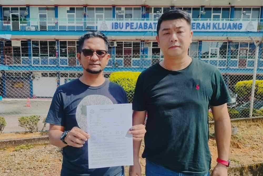 Sheikh Umar (kiri) menunjukkan laporan polis yang dibuat di IPD Kluang pada Sabtu.