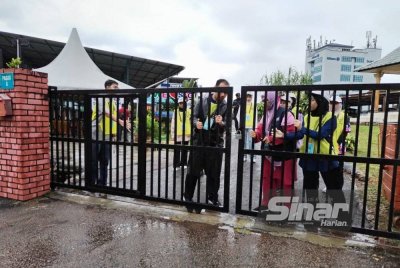 Petugas pusat mengundi Sekolah Agama Gunung Lambak, Kluang, menutup pintu pagar menandakan tamatnya tempoh mengundi bagi PRK Mahkota.