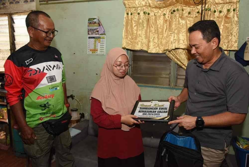 Fadzli (kanan) menyampaikan sumbangan pada Nurul Batrisya di kediaman keluarganya