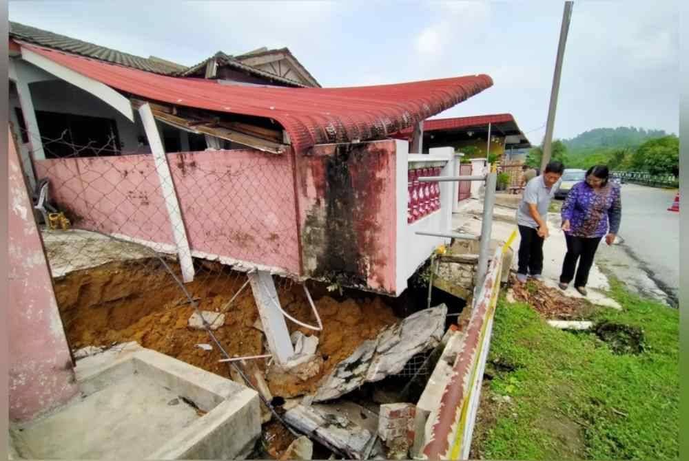 Bavani (kanan) ketika meninjau keadaan tanah mendap yang menjejaskan empat rumah di Taman Teja di sini pada Ahad.