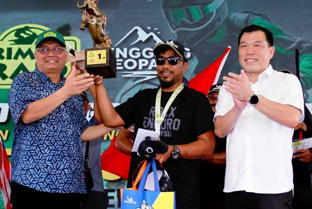 Shamsul Anuar (kiri) menyampaikan hadiah kepada Juara Rimba Raid 2024 Kategori A mewakili Malaysia Mohd Zulkarnain Tahir (tengah) di Resort Tasik Raban Lenggong hari ini. Foto Bernama