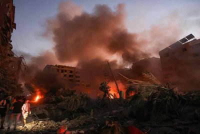 Asap mengepul dari runtuhan yang membara ketika orang ramai berkumpul di tempat kejadian serangan udara Israel di kejiranan Haret Hreik di pinggir selatan Beirut. Foto AFP