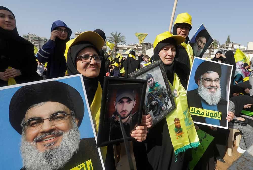 Penyokong Hizbullah memegang potret Hassan Nasrallah semasa mengadakan perarakan di di bandar Nabatiyeh pada tahun 2022. - AFP
