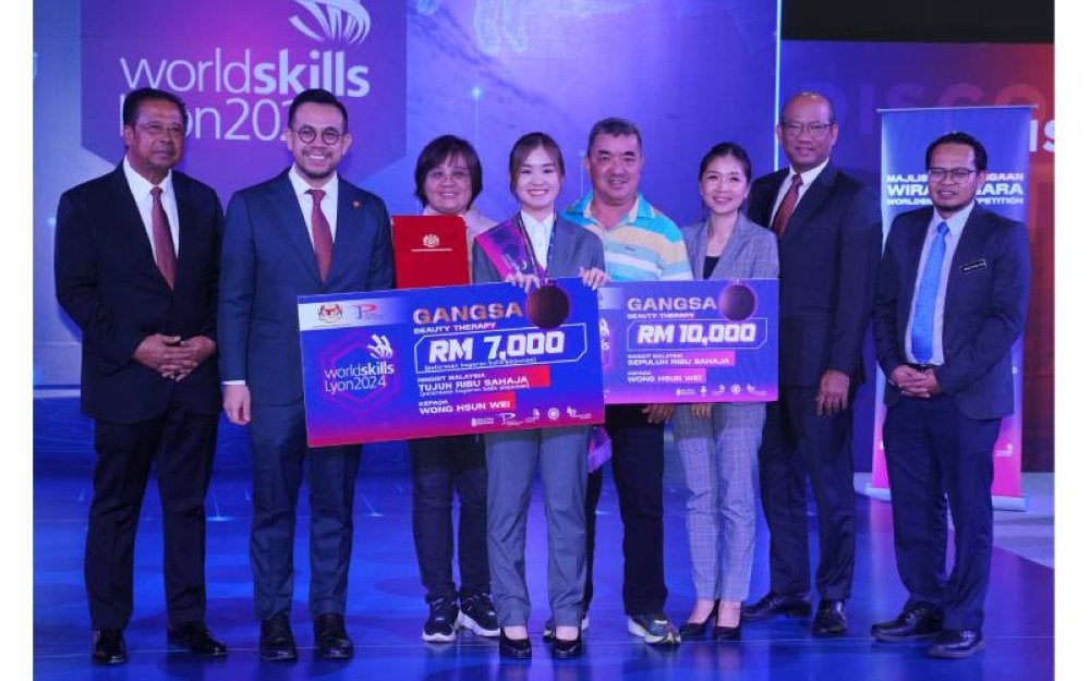 Steven Sim (dua dari kiri) menyampaikan replika cek kepada Wong Hsun Wei (empat dari kiri) pada Majlis Penghargaan Wira Negara World Skills Competition (WSC) Lyon 2024.