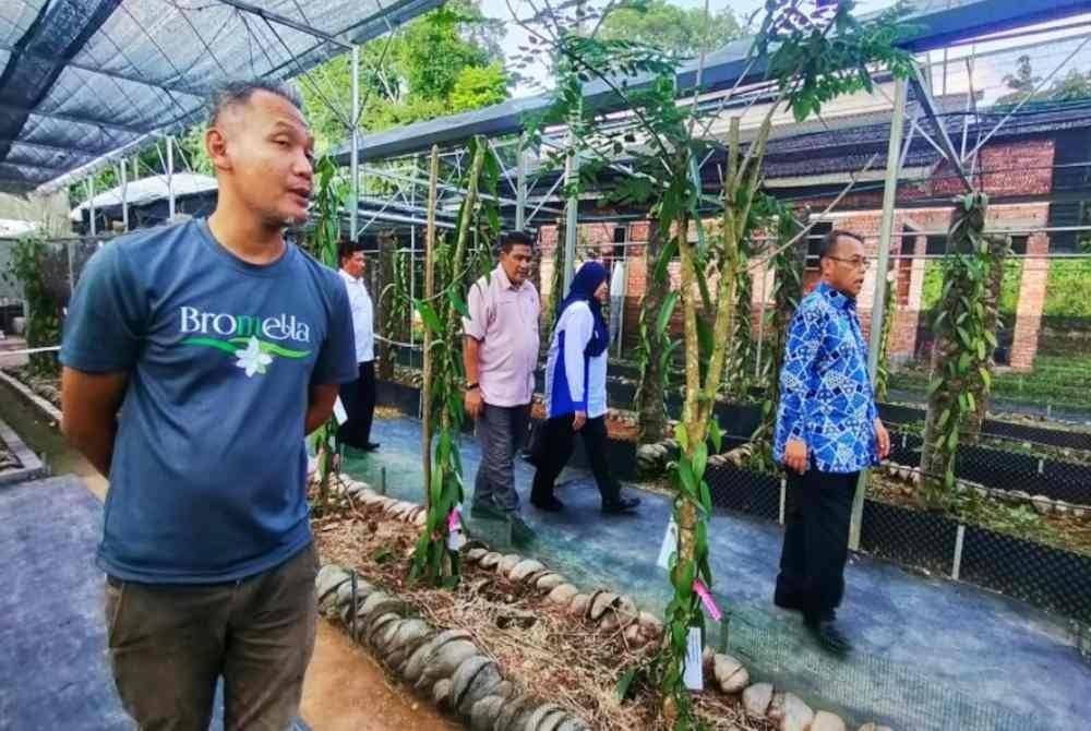 Abdul Fattah (kanan) ketika meninjau ladang vanila yang diusahakan Mohamad Feisal (kiri) di Temerloh pada Isnin.