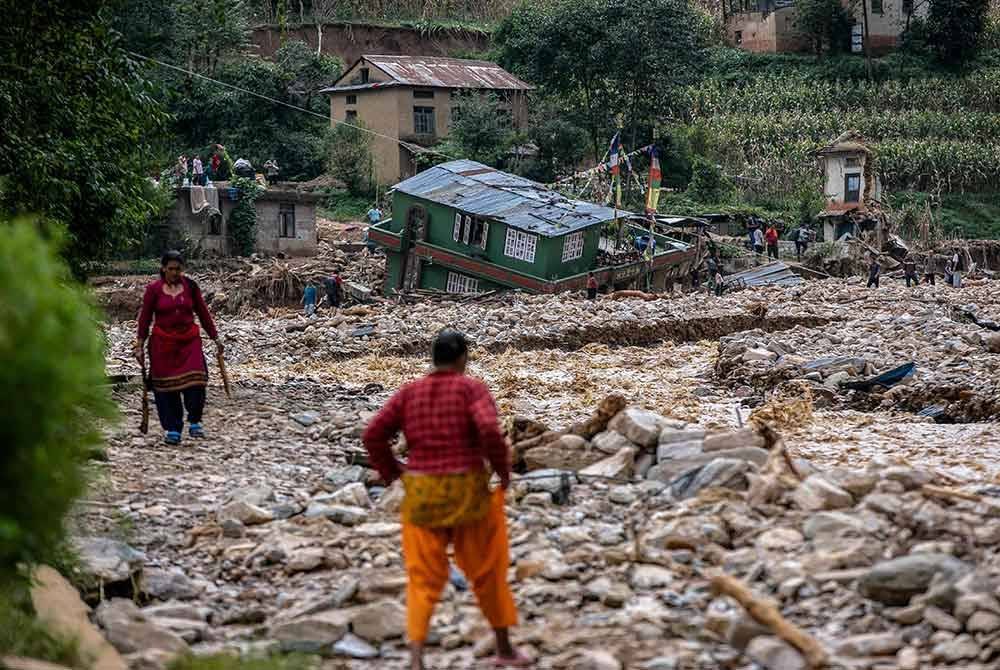 Penduduk berjalan melalui kawasan terjejas berikutan banjir monsun di perkampungan Roshi di daerah Kavre, Nepal. Foto AFP