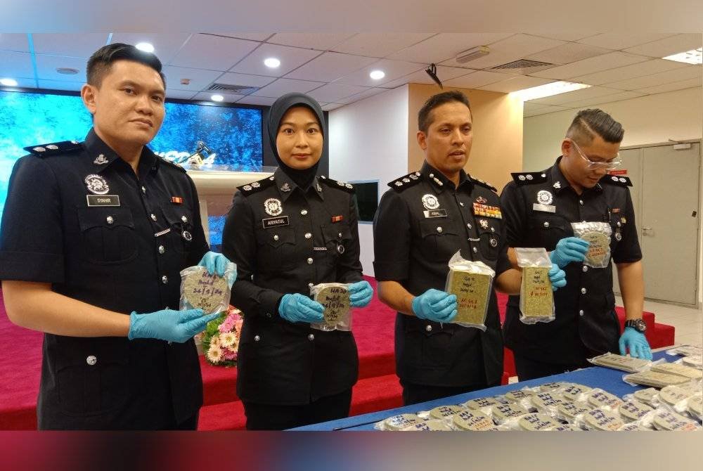 Mohd Iqbal (kiri) menunjukkan antara dadah yang dirampas menerusi tangkapan dan serbuan di sebuah kondominium dekat Petaling Jaya pada Khamis lalu.