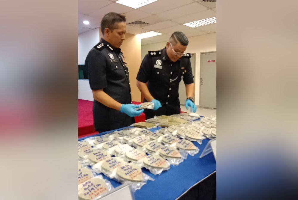 Mohd Iqbal (kiri) menunjukkan antara dadah yang dirampas menerusi tangkapan dan serbuan di sebuah kondominium dekat Petaling Jaya pada Khamis lalu.