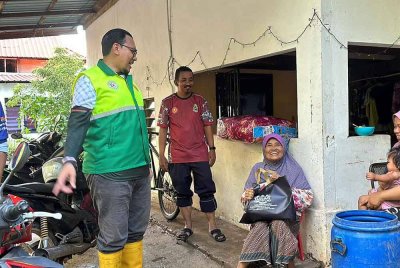 Ahli Parlimen Alor Setar, Afnan Hamimi Taib Azamudden (kiri) semasa turun menyantuni mangsa banjir di Kampung Suka Menanti, Alor Setar pada Selasa.