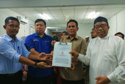 Pengerusi Persatuan Penjaja dan Peniaga Kecil Melayu Daerah Batang Padang, Abdul Rashid Osman (kanan) menyerahkan memorandum bantahan berhubung sistem penyuaraian baharu aliran trafik satu hala di bandar Tapah kepada Ishsam (dua dari kanan).