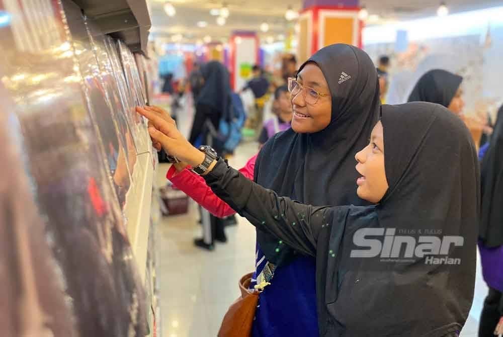 Pengunjung teruja melihat buku pelbagai genre yang tersedia di rak buku.