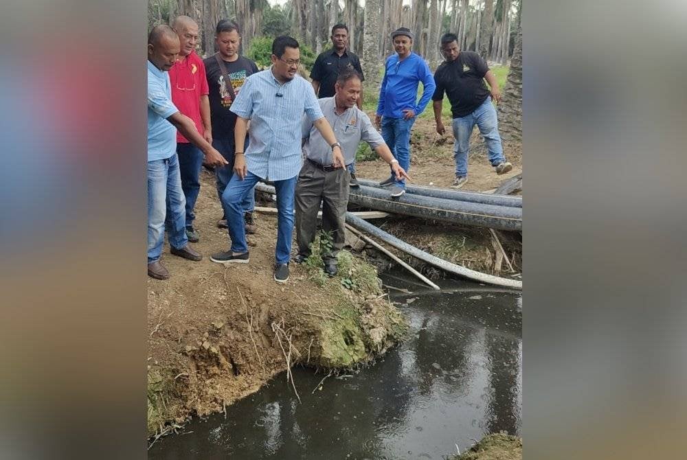 Harrison (depan tengah) menunjukkan pencemaran parit akibat pembuangan sisa najis ayam dari sebuah kilang di Kampung Simpang 3 Jeram di sini pada Khamis.