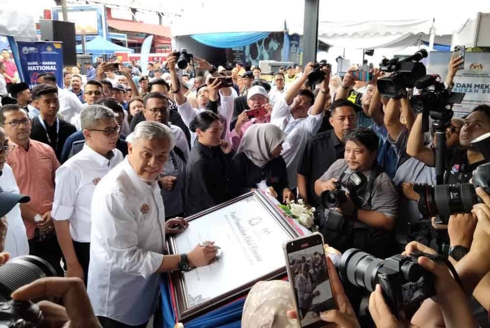 Ahmad Zahid menandatangani plak sebagai gimik inisiatif Pusat Pemindahan Kekal Bencana (PPKB) di Taman Kota Jaya, Kota Tinggi pada Khamis.