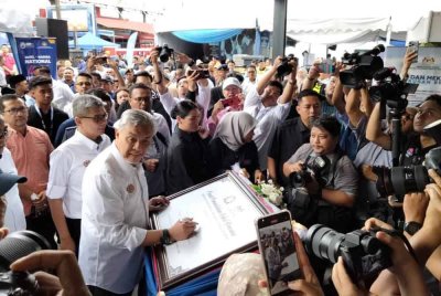 Ahmad Zahid menandatangani plak sebagai gimik inisiatif Pusat Pemindahan Kekal Bencana (PPKB) di Taman Kota Jaya, Kota Tinggi pada Khamis.