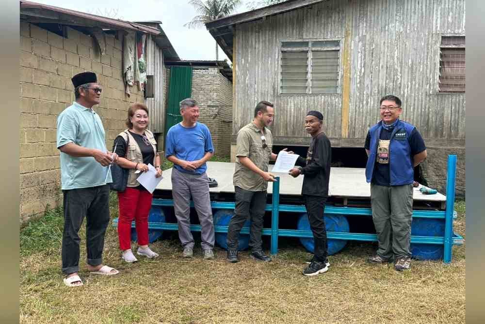 Penyerahan rakit kepada penduduk, Rozi Daud (tiga dari kiri) di Tersang, Rantau Panjang.