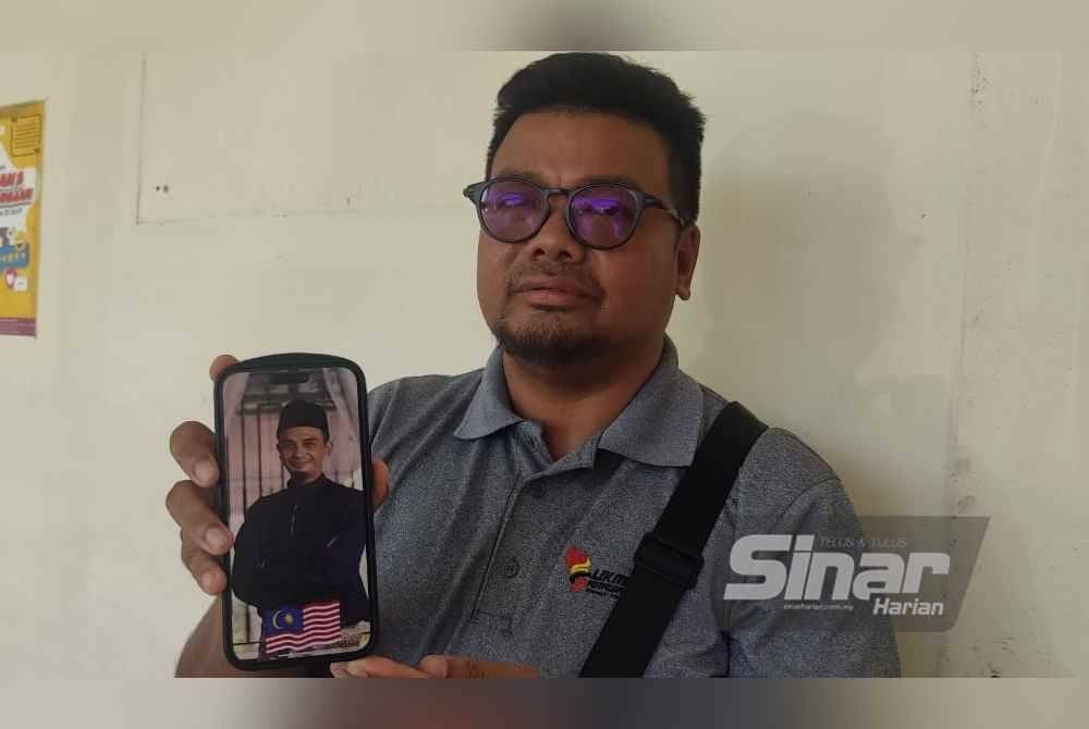 Khairil Ajhar menunjukkan gambar adiknya, Allahyarham Khairul Nizam semasa ditemui di Jabatan Forensik Hospital Sultanah Bahiyah, Alor Setar pada Jumaat.