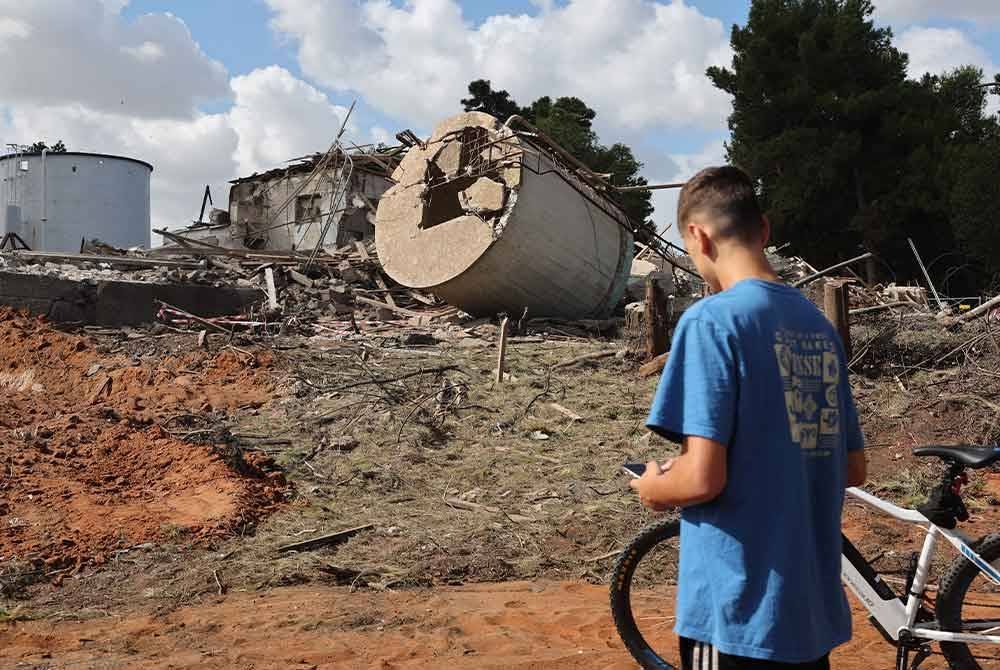 Seorang remaja lelaki melihat kesan runtuhan bangunan di Hod Hasharon selepas serangan peluru berpandu Iran ke atas Israel.