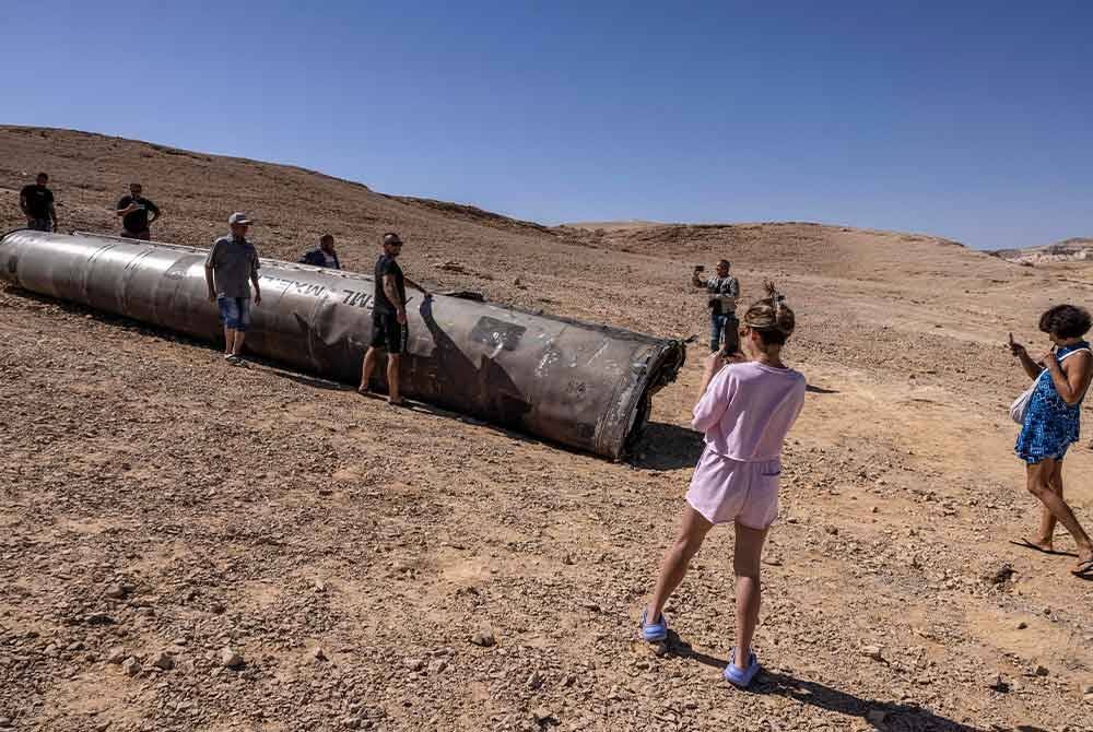 Orang ramai bergambar dengan sisa peluru berpandu Iran di padang pasir Negev berhampiran Arad.