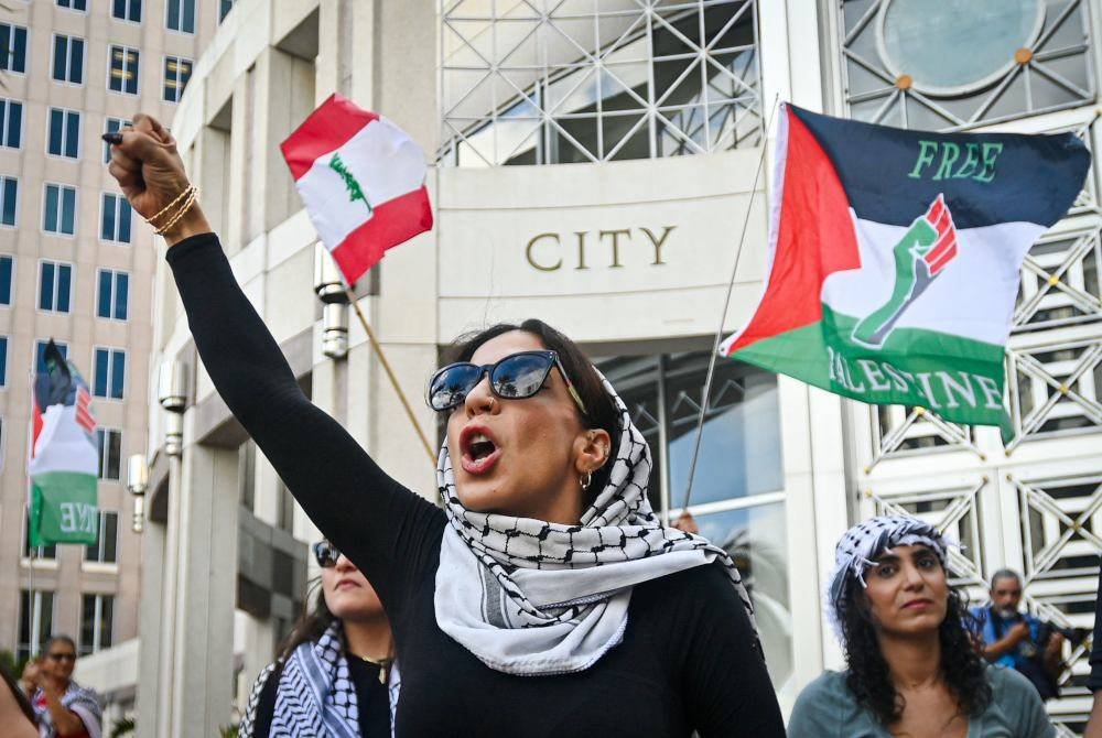 Beberapa penunjuk perasaan mengibarkan bendera Palestin.