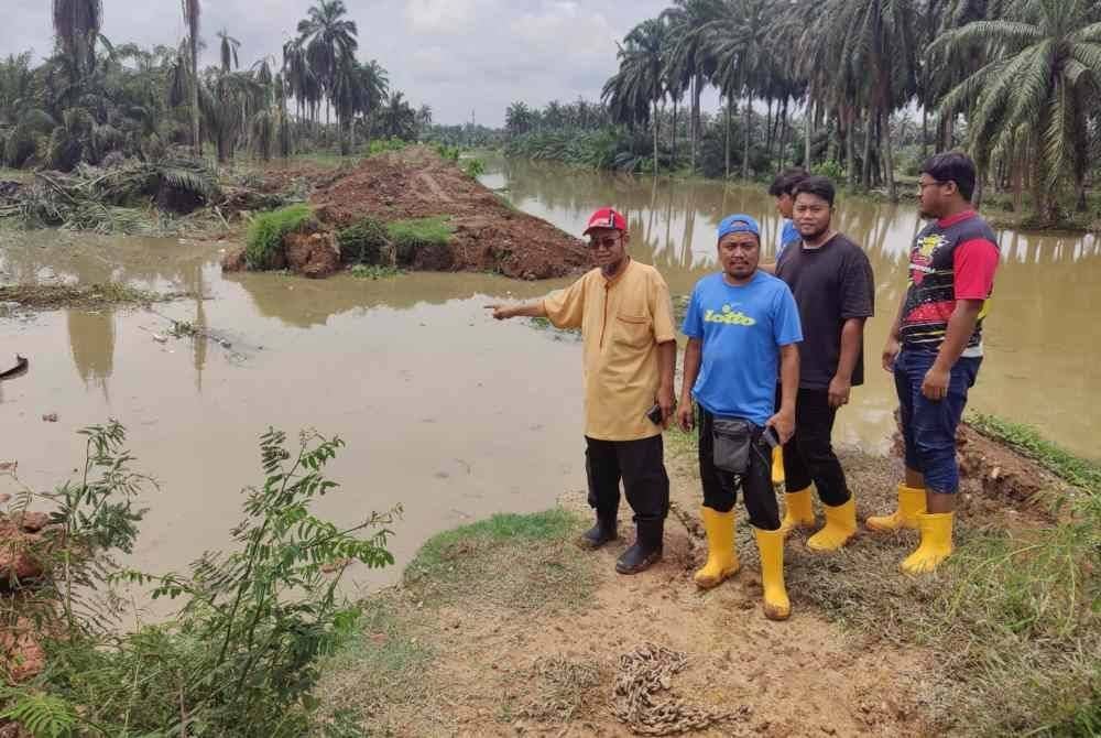 Mohamad Afandy (kiri) menunjukkan keadaan ban pecah di lembangan Sungai Buloh pada Ahad.