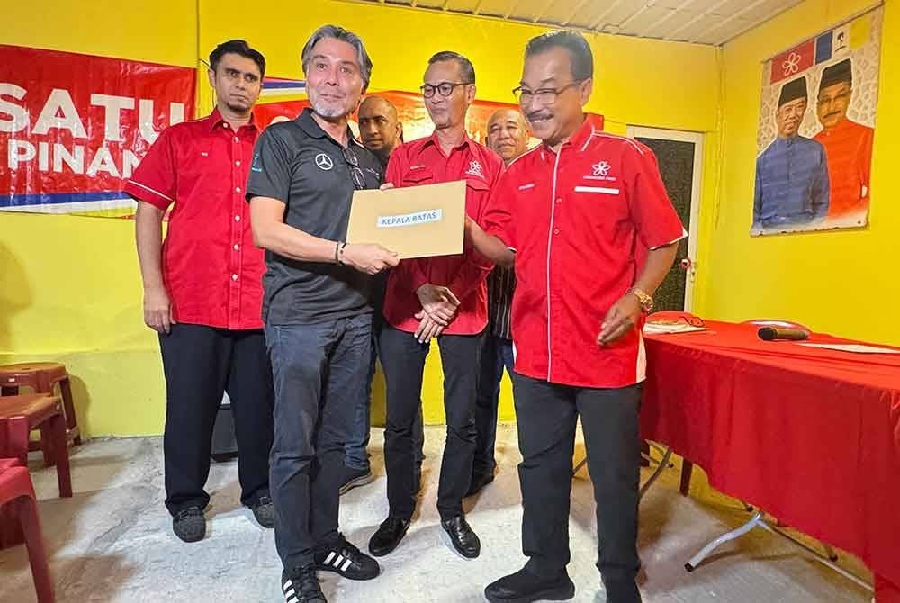Zulkefli (kanan) menyerahkan surat pengesahan layak bertanding kepada Khaliq Mehtab yang juga bekas ADUN Bertam.