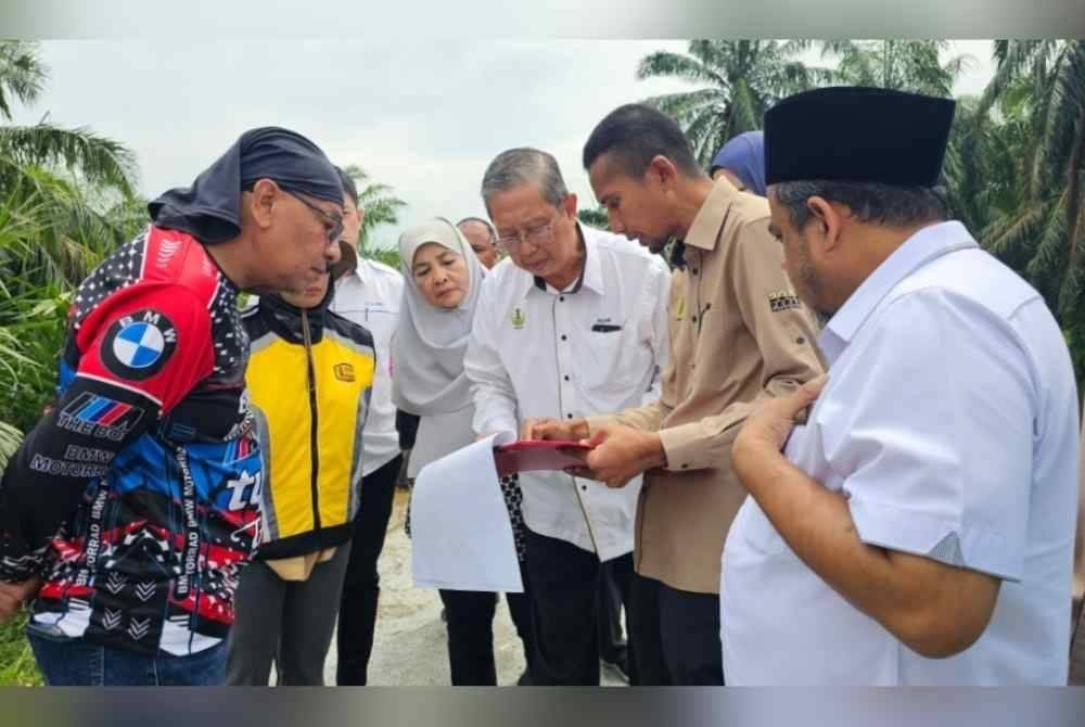 Mohammad Nizar (tengah) mendengar penerangan daripada pihak JPS berhubung operasi pam bergerak di Kampung Selekoh, Bagan Serai.