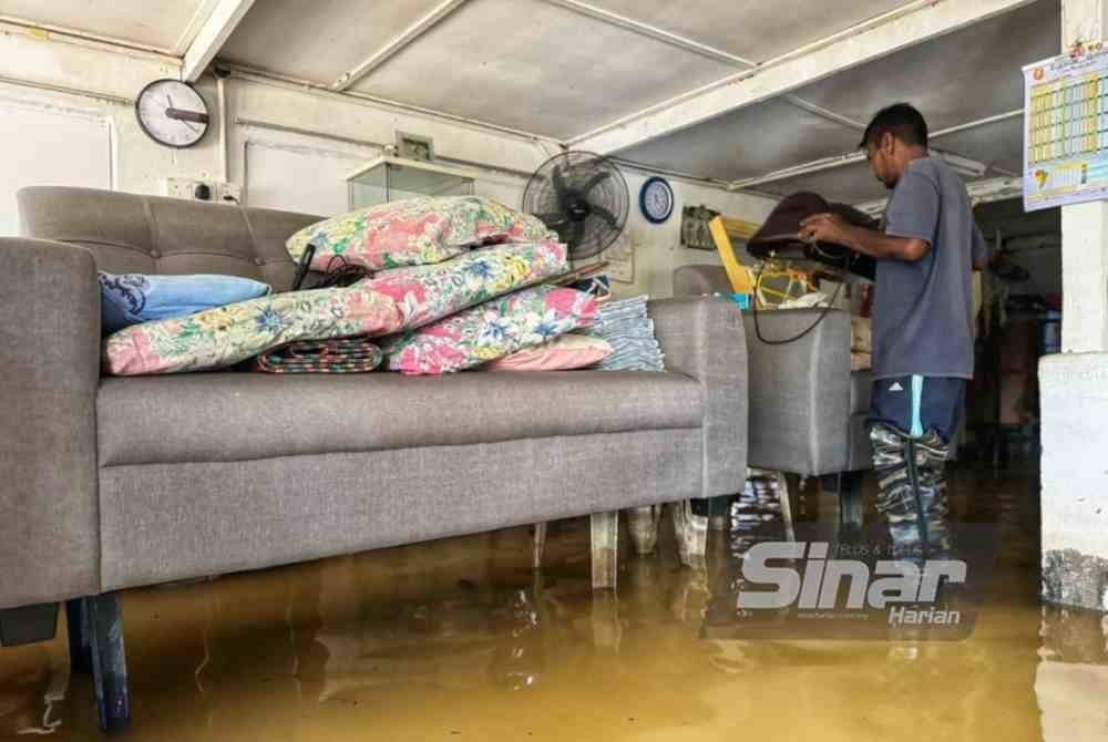 Zain menyusun barangan rumahnya di tempat tinggi untuk mengelakkan ditenggelami air banjir.