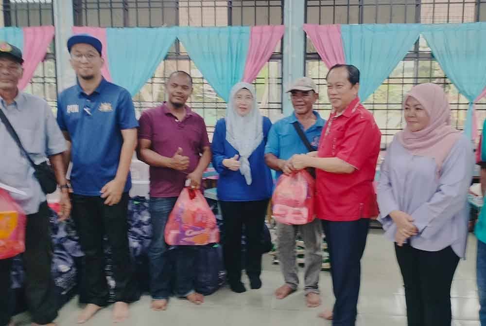 Khairin-Nisa (kanan) dan Ahmad (dua kanan) menyampaikan bantuan di PPS Sekolah Kebangsaan (SK) Seri Anom, Sanglang, Pontian.