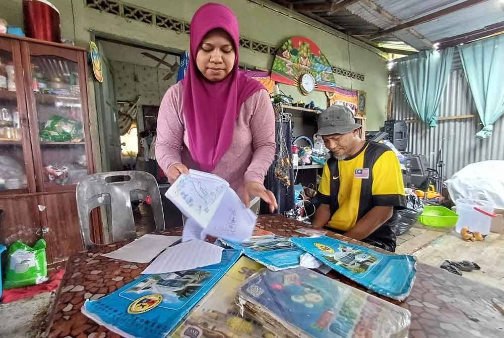 Farah Umiah melihat buku sekolah anaknya yang basah kerana tidak sempat untuk dialihkan.
