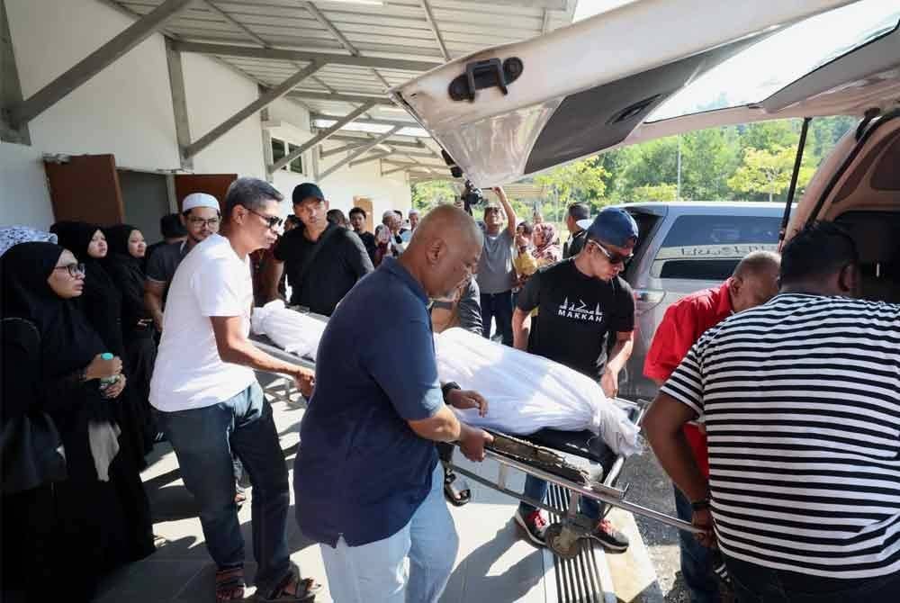 Jamaludin (tengah) membawa jenazah anaknya ketika proses membawa pulang dari Unit Forensik Hospital Dungun pada Khamis.