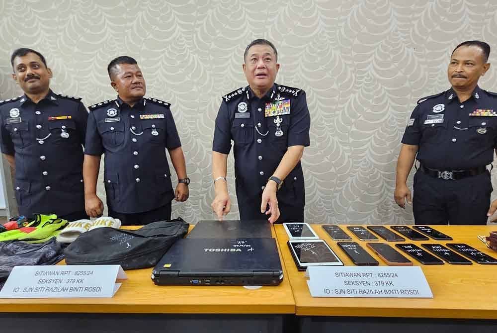 Polis menunjukkan pelbagai barangan termasuk komputer riba yang dirampas daripada Geng Dinesh.