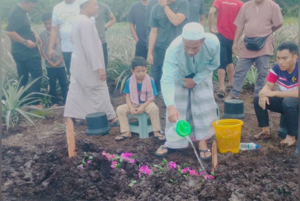 Md Tukirin menyiram air di pusara anaknya Muhammad Akmal di Tanah Perkuburan Islam Kampung Parit Baru, Muar.