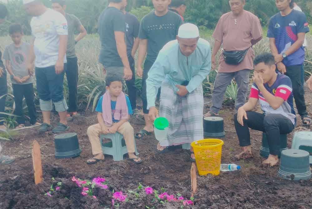 Md Tukirin menyiram air di pusara anaknya Muhammad Akmal di Tanah Perkuburan Islam Kampung Parit Baru, Muar.
