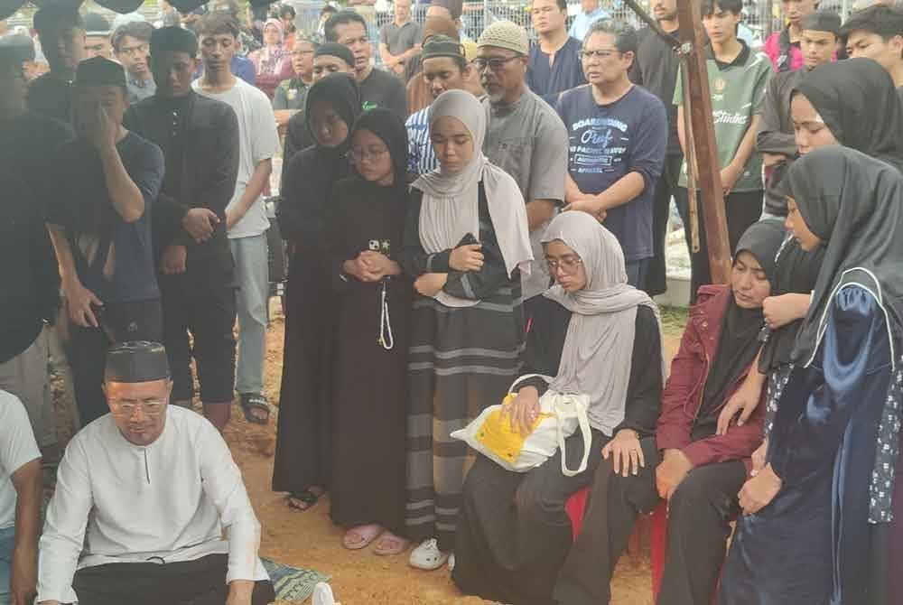 Ku Azmi (kiri) dan Hafizah (duduk, kanan) ketika membaca talkin semasa pengebumian Allahyarham Ku Adib di Tanah Perkuburan Islam Rauthatul 'Aliyah, Saujana Utama di sini pada Khamis.
