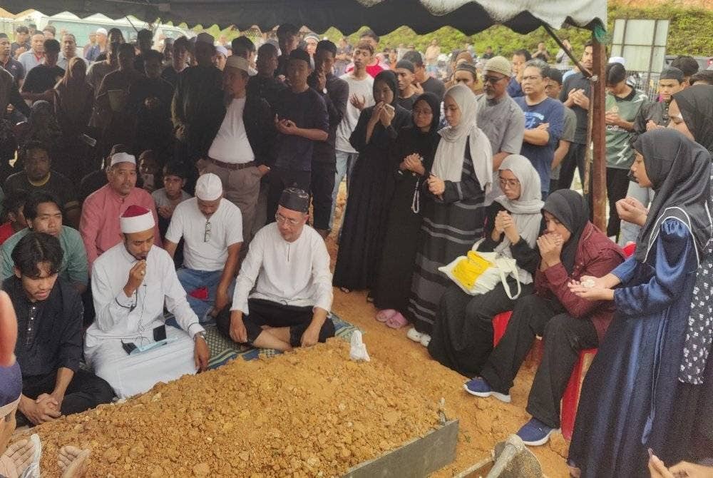 Ku Azmi (duduk kanan) semasa pengebumian Allahyarham anaknya di Tanah Perkuburan Islam Rauthatul 'Aliyah, Saujana Utama di sini pada Khamis.