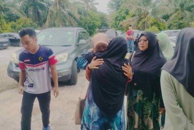 Ibu Muhammad Akmal, ditenangkan suadara mara sebaik tiba di Kampung Parit Baru, Muar pada petang Khamis.