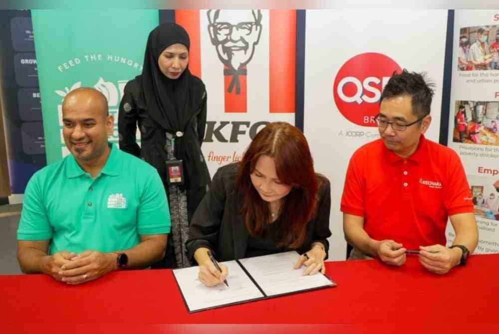 Ketua KFC Malaysia, Kemboja & Brunei, Loi Liang Tok (tengah) menandatangani perjanjian perkongsian Projek Harvest bersama Daniel dan Justin.