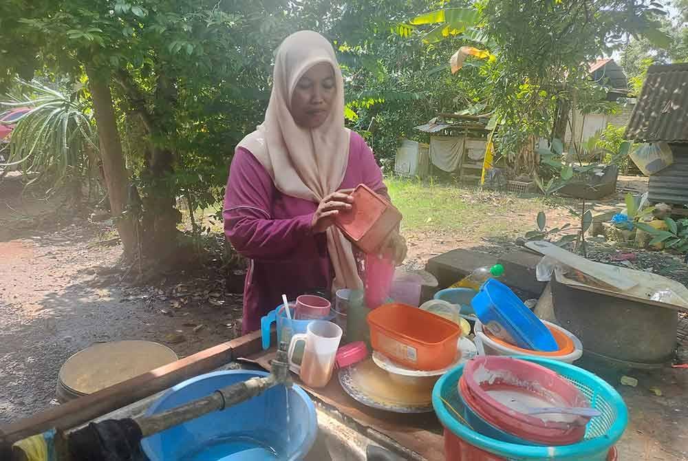 Mashitoh membasuh pinggan mangkuk kotor yang berlungguk di luar rumahnya.