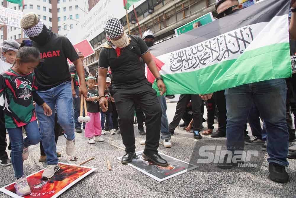 Peserta demonstrasi memijak poster memaparkan wajah Benjamin Netanyahu. Foto Sinar Harian-ROSLI TALIB