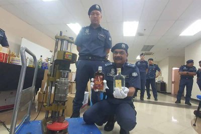 Roselan (kanan) menunjukkan botol minuman keras tiruan dan mesin yang dirampas dari sindiket.